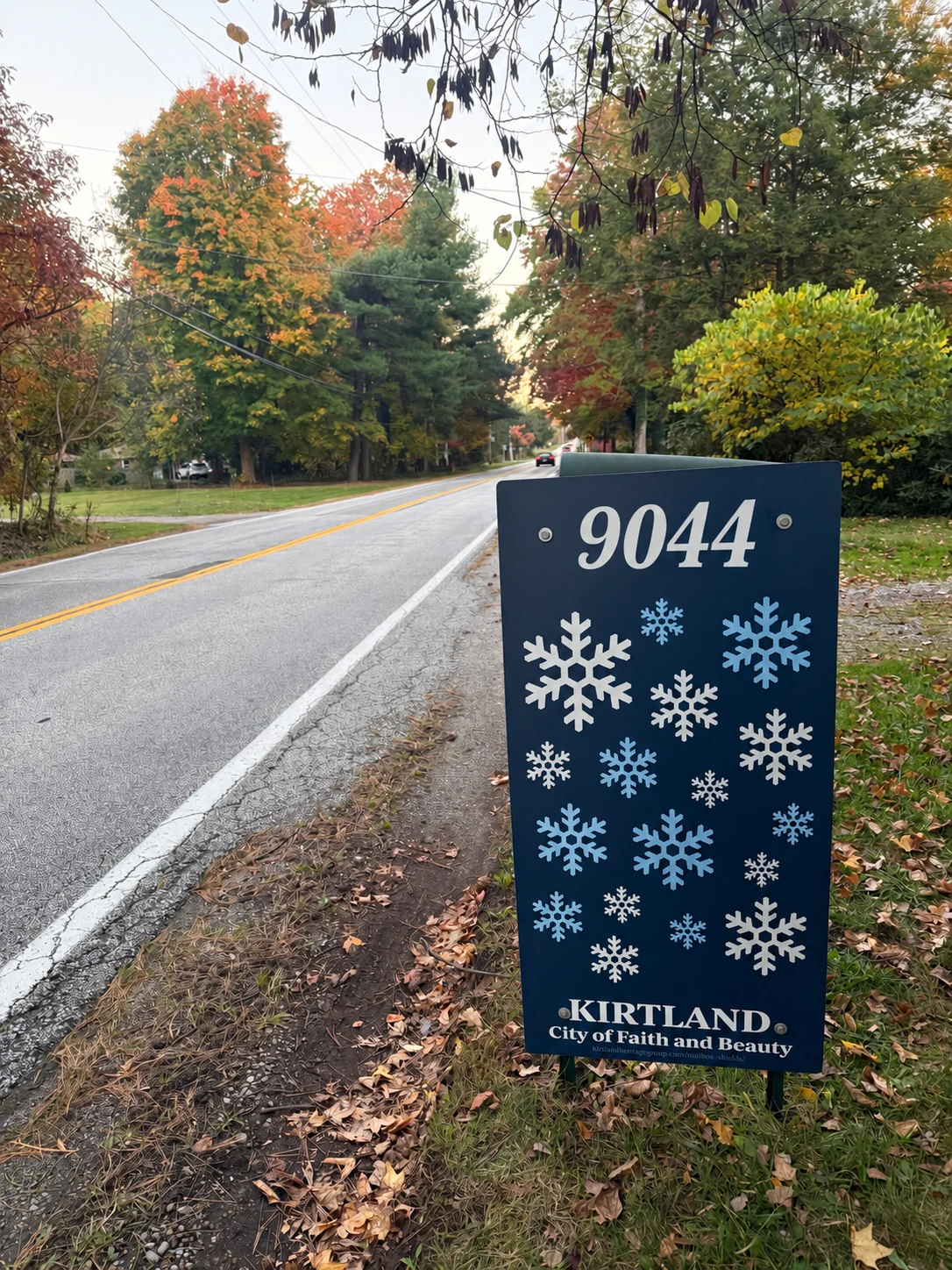 Snowflake mailbox shield with digitally added example address 9044, shown along a tree-lined road